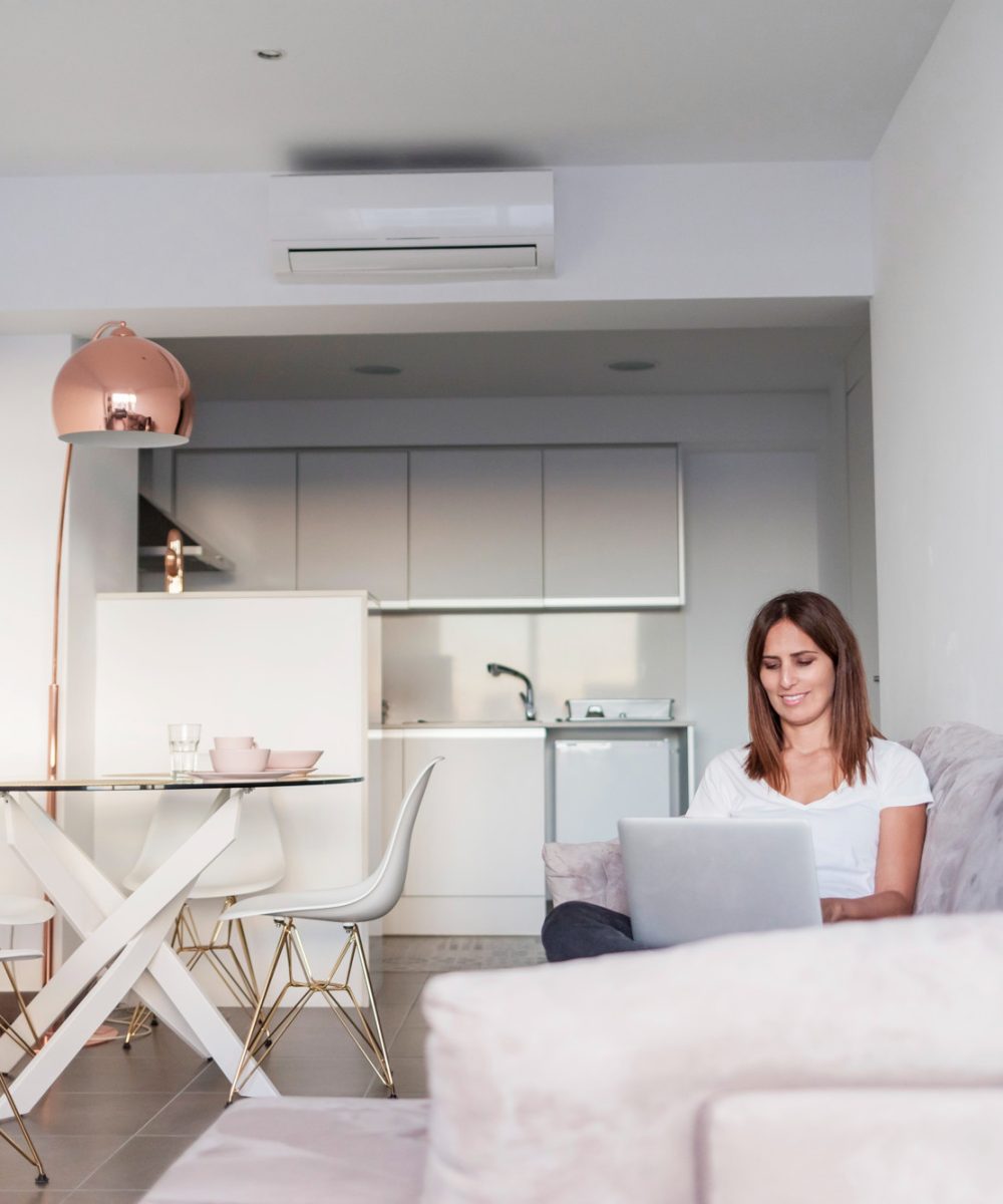 mujer-adulta-sentada-sofa-mientras-usando-computadora-portatil-sosteniendo-taza-te